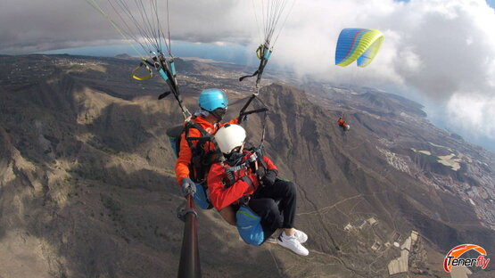 Shared adventure: Couple enjoying paragliding over the rocky mountain of El Conde in Tenerife